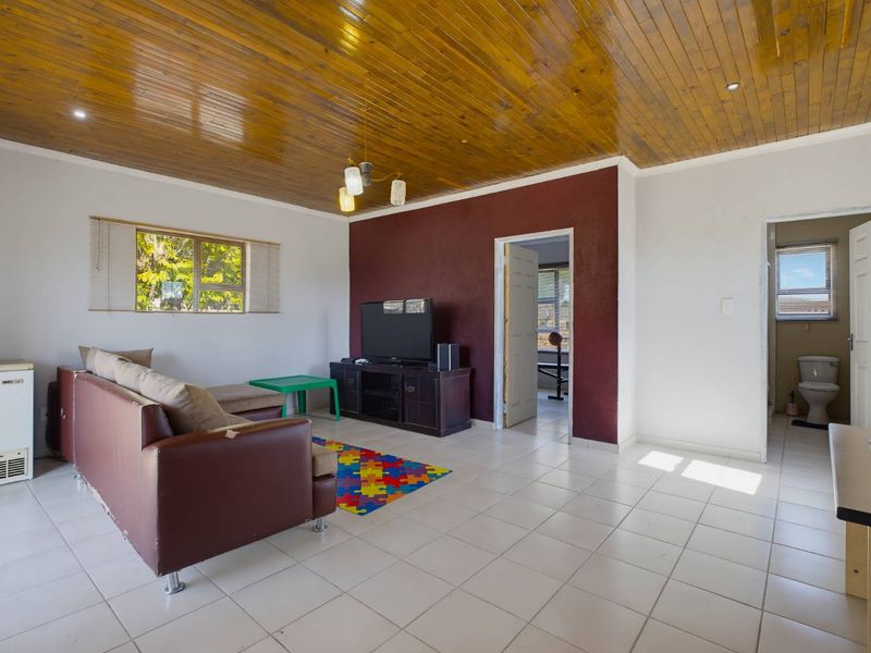 A living room featuring ceramic floor tiles, a wooden tongue and groove ceiling, and a dark accent wall, providing a functional living space.
