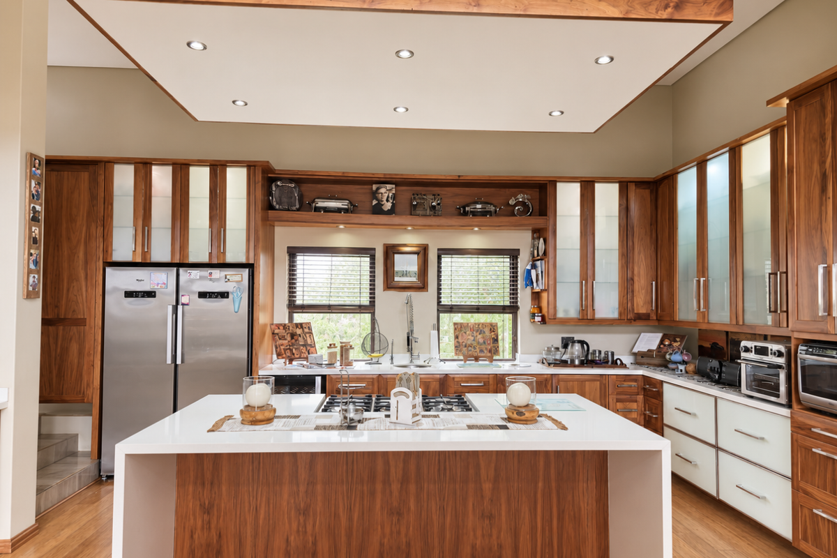 A modern kitchen featuring high-quality wooden cabinetry, a central island with a stone countertop, integrated appliances, and a distinctive wooden ceiling feature with recessed lighting.