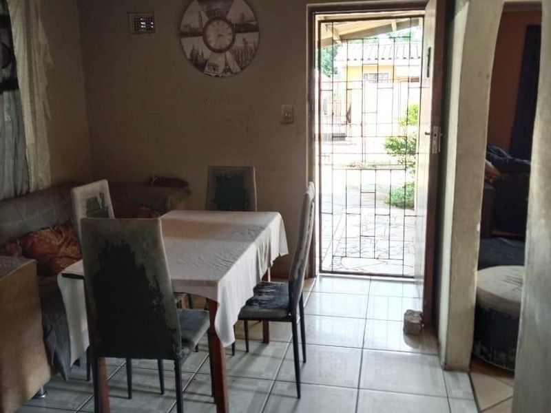 Dining area featuring tiled flooring, a timber ceiling, and an arched entryway leading to an adjacent space with direct access to the exterior.