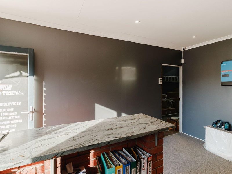 A professional office space featuring a brick-based service counter with a stone top, recessed lighting, and integrated security and power infrastructure.