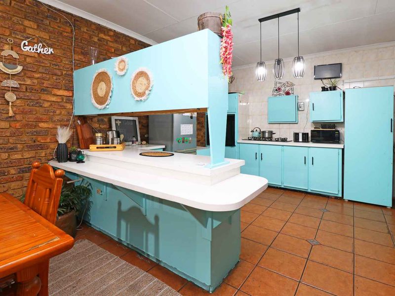 Kitchen featuring exposed brick walls, tiled flooring, and a breakfast bar, offering a functional layout with ample built-in cabinetry.