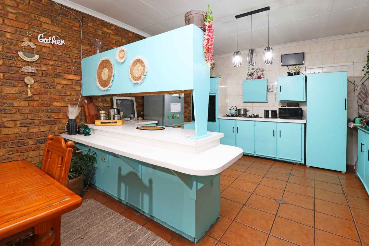 Kitchen featuring exposed brick walls, tiled flooring, and a breakfast bar, offering a functional layout with ample built-in cabinetry.