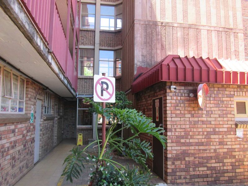 Exterior view of an apartment building complex featuring face brick walls, a metal awning, and a paved walkway area.