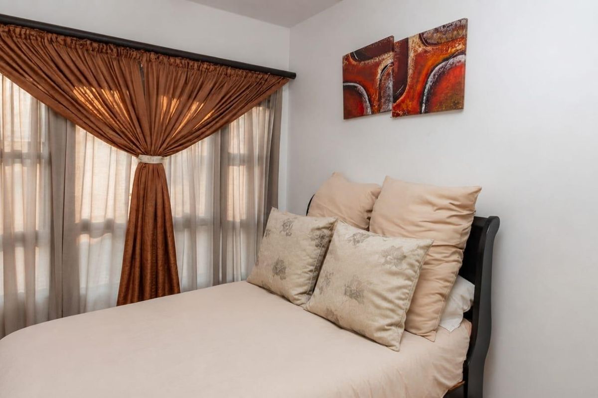 A cozy bedroom featuring a window with installed curtain rods and neutral wall finishes.