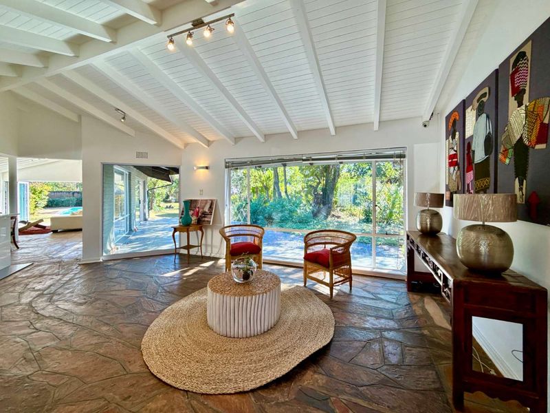 Spacious living area featuring unique flagstone flooring, exposed white beam ceilings, and large sliding glass doors providing abundant natural light and garden views.