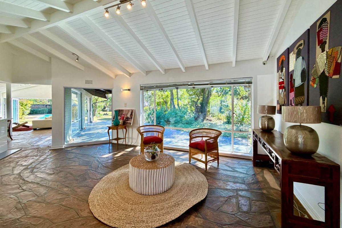 Spacious living area featuring unique flagstone flooring, exposed white beam ceilings, and large sliding glass doors providing abundant natural light and garden views.