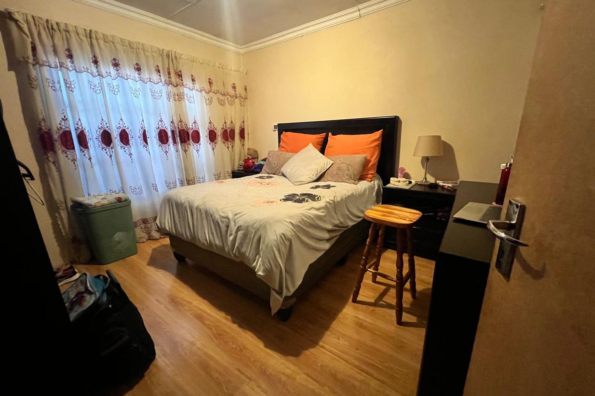 A standard bedroom featuring laminate flooring and decorative coving, providing a functional space for rest.