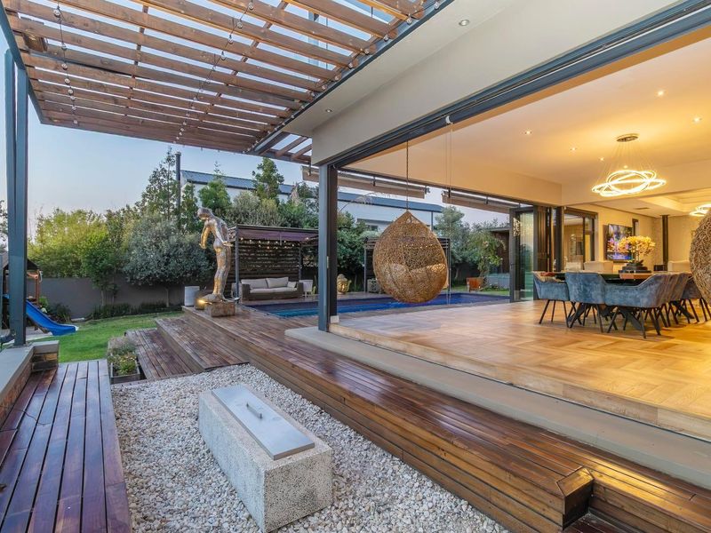 Expansive outdoor timber deck featuring a pergola, integrated fire pit, and seamless transition to the swimming pool and open-plan living area.