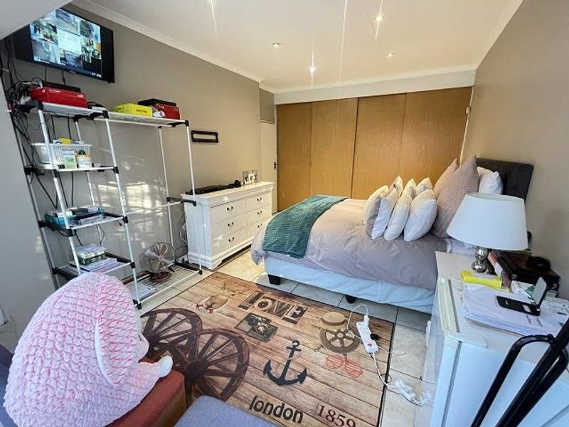 A bedroom featuring built-in wooden cupboards, tiled flooring, and recessed ceiling lighting.