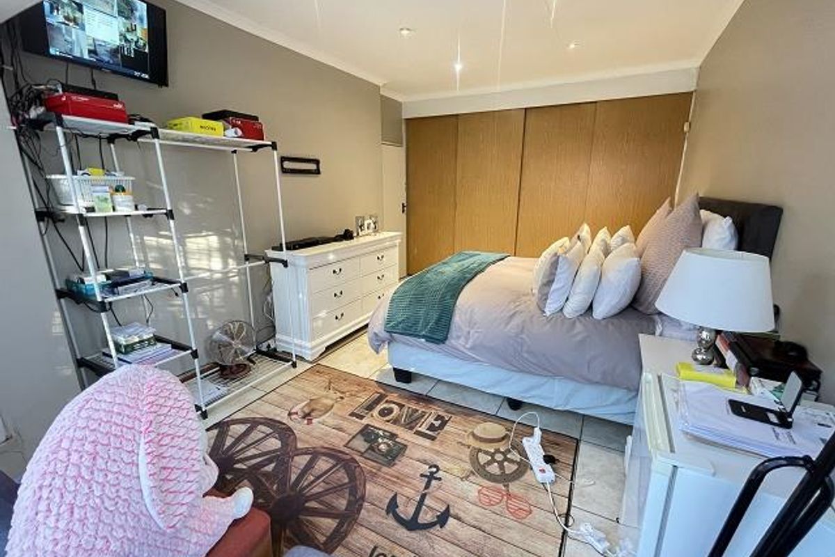 A bedroom featuring built-in wooden cupboards, tiled flooring, and recessed ceiling lighting.