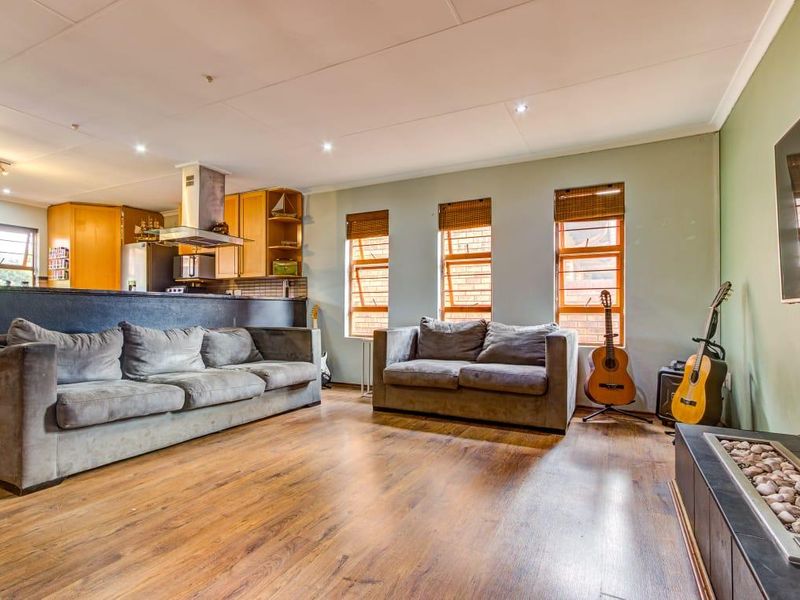 Spacious open-plan living area featuring laminate flooring, a built-in fireplace, and a functional kitchen with a breakfast counter and modern extractor fan.