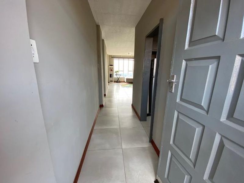 A bright, tiled hallway leading from the entrance into the main living area of the apartment.