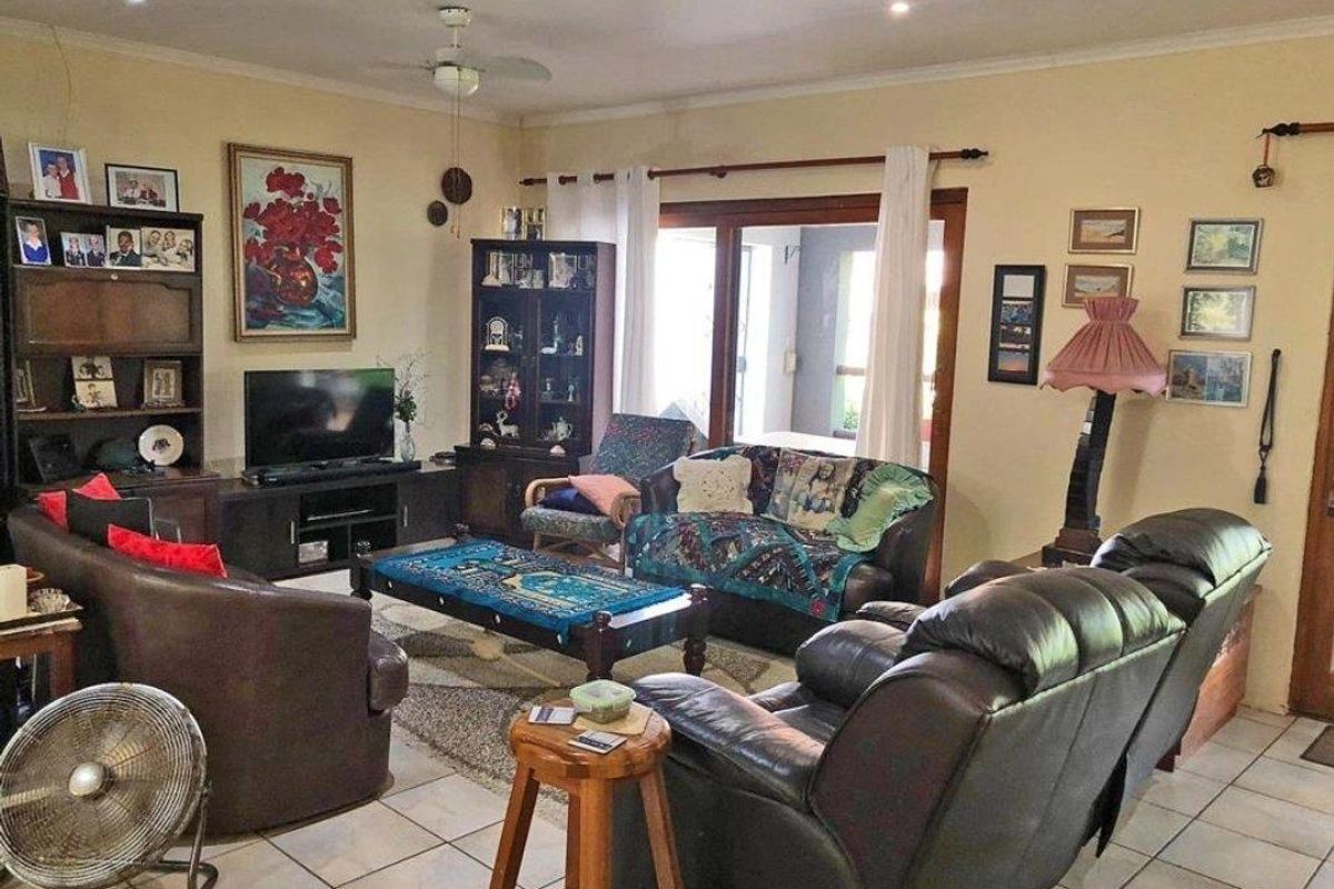 A spacious living room featuring tiled flooring, recessed downlighting, and a ceiling fan, with direct access to an outdoor area through sliding glass doors.