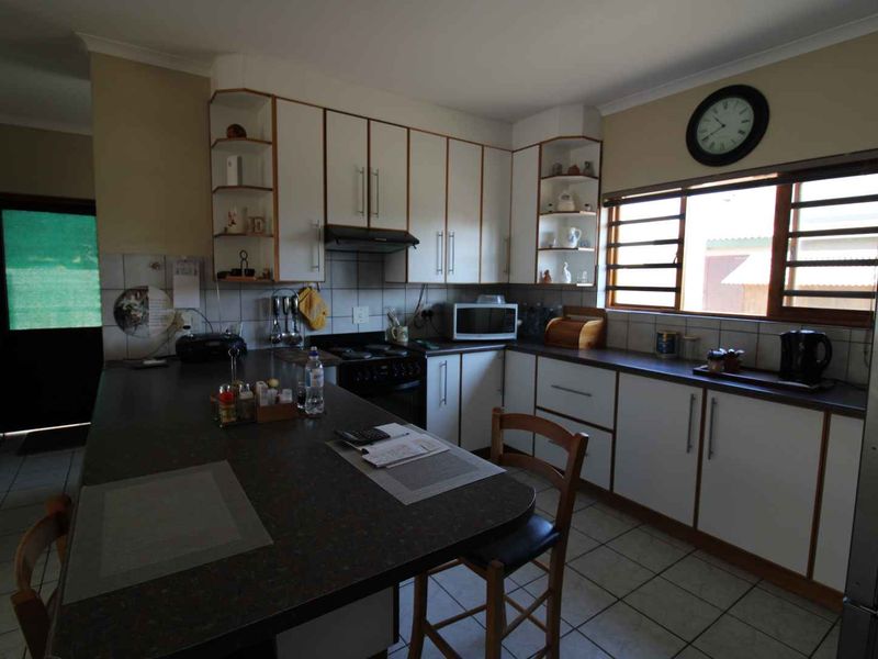 A functional kitchen featuring laminate countertops, built-in cabinetry, and tiled flooring, offering a practical layout with ample storage and workspace.