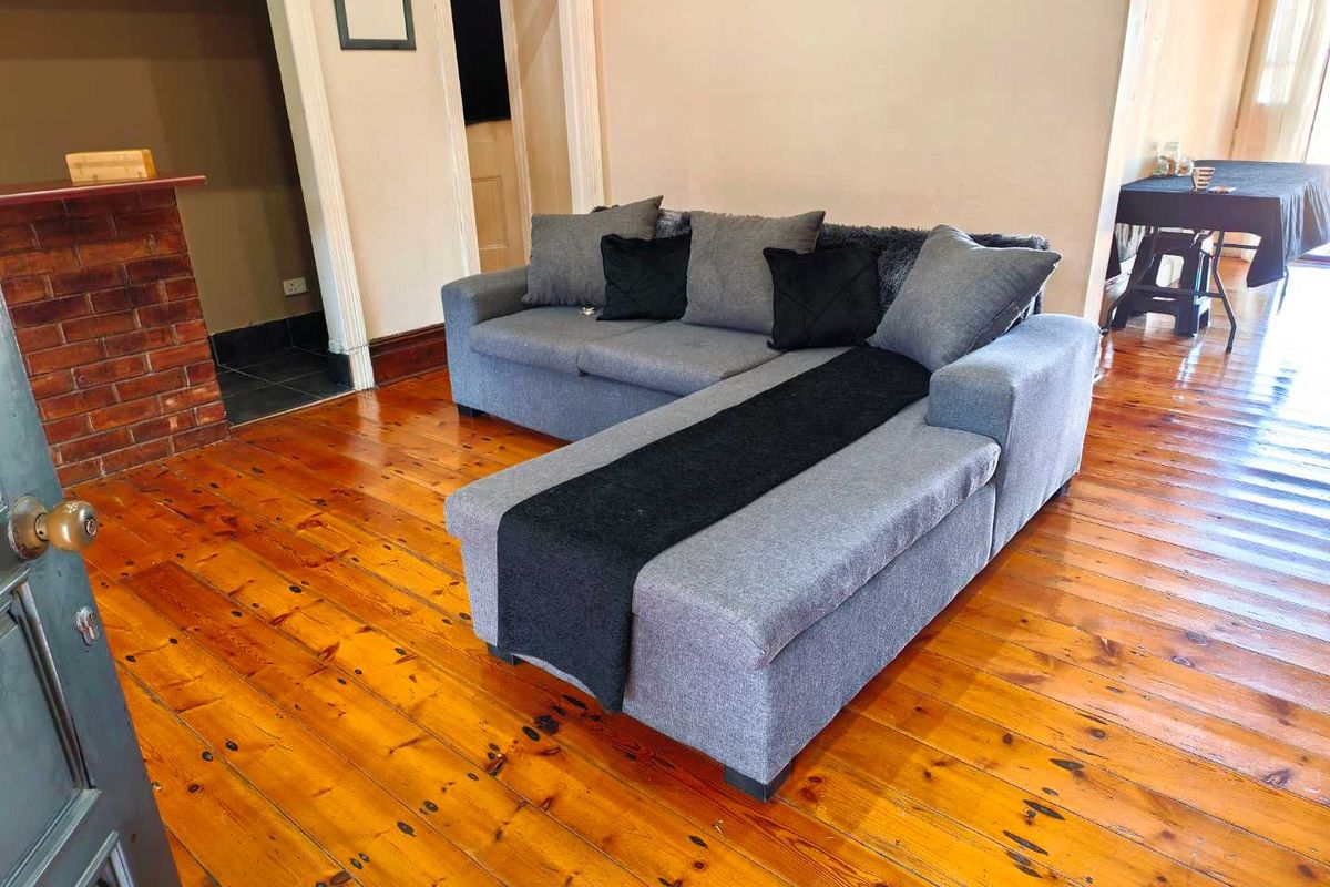 Living room featuring original timber flooring and an exposed brick fireplace, offering a classic foundation for interior updates.