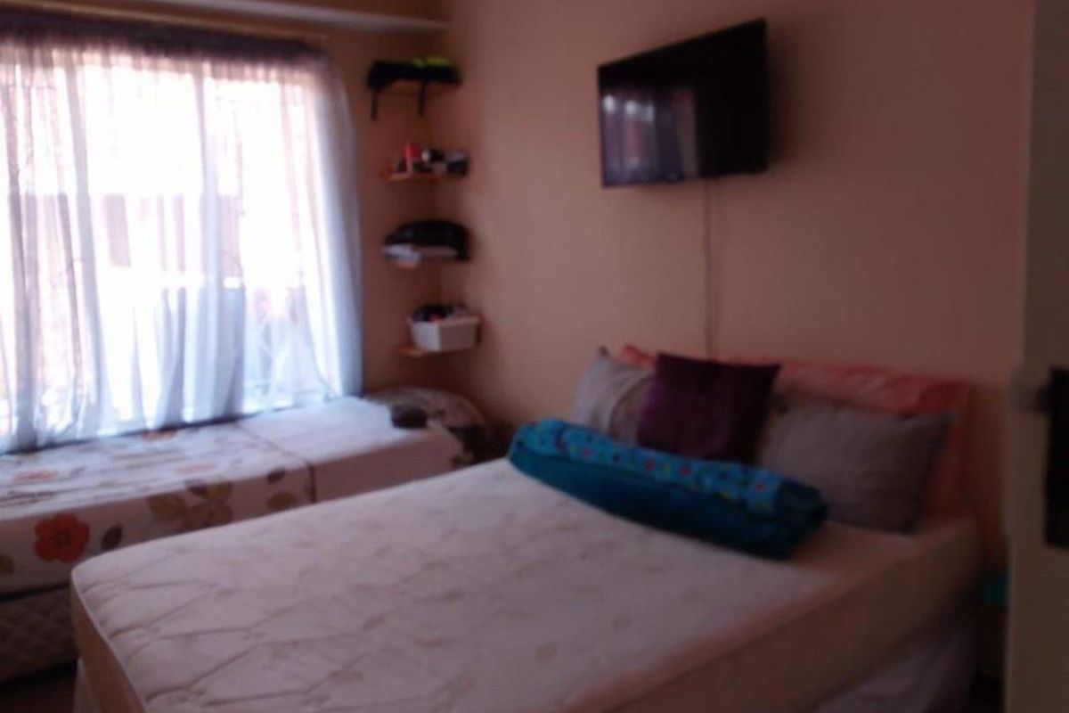 A bedroom featuring a window with curtains and wall-mounted shelving.
