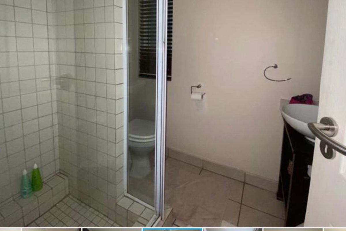 A functional bathroom featuring a tiled shower enclosure with glass door, a pedestal-style basin, and a standard toilet.
