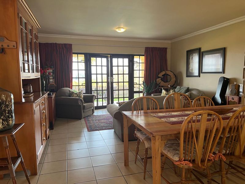 Open plan living and dining area featuring tiled flooring and double french doors leading to the outdoor space.