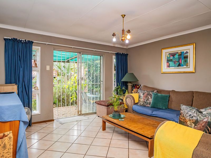 A comfortable living room featuring tiled flooring and a sliding glass door that provides direct access to the outdoor patio area.