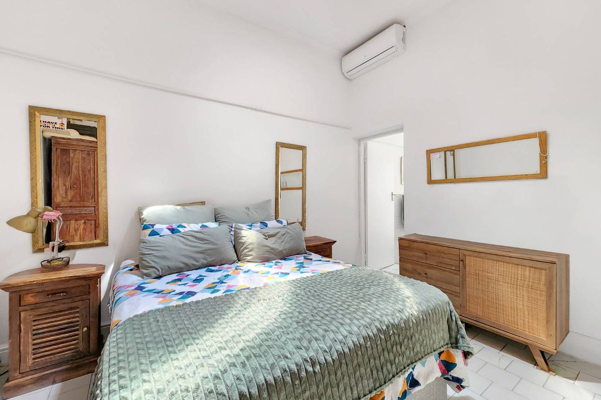 A bright bedroom featuring tiled flooring and a wall-mounted split-system air conditioning unit.