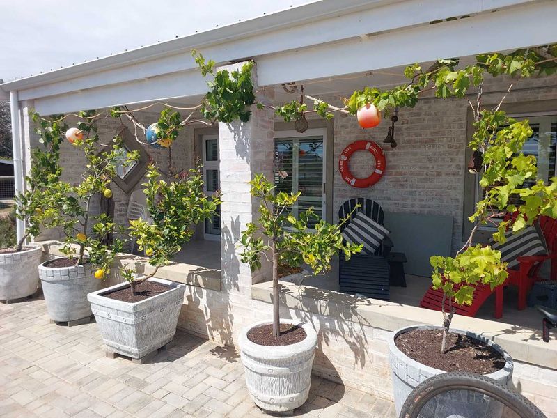 A covered outdoor patio area featuring brick wall finishes and paved flooring, providing a pleasant space for relaxation.