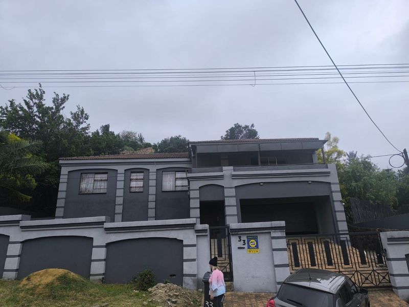 Front elevation of a two-story residential property featuring a perimeter wall, security gate, and an integrated garage.