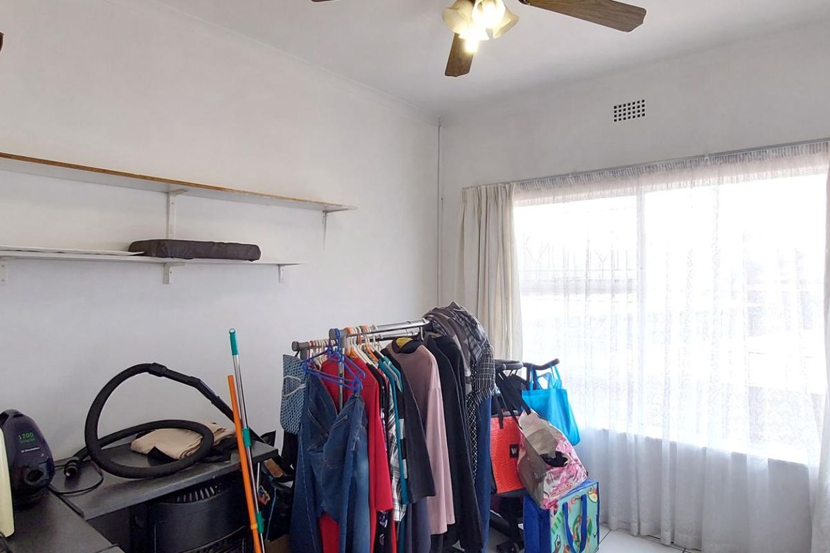 A bedroom featuring a ceiling fan, built-in shelving, and a built-in cupboard, providing functional storage space and natural light.