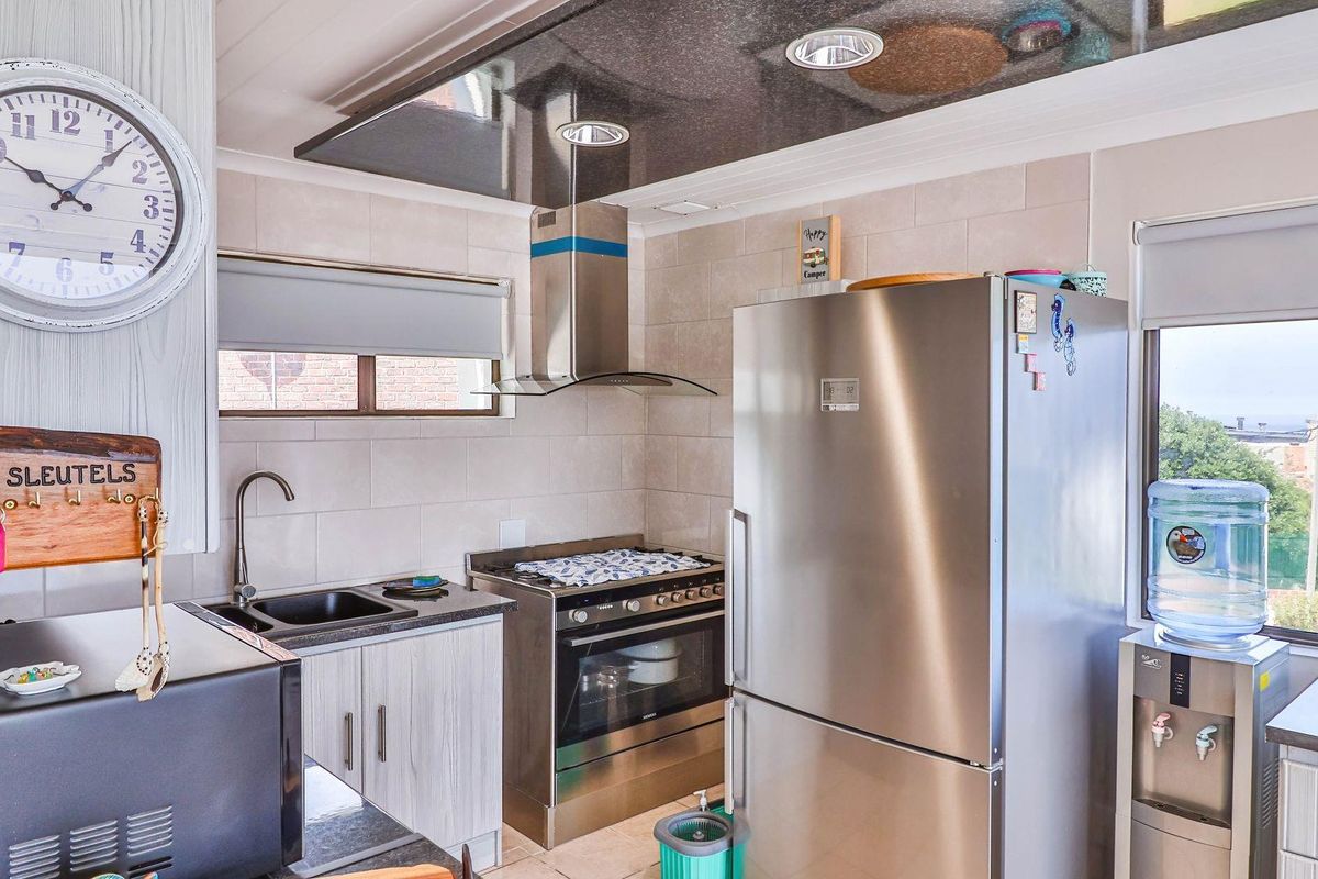 Compact kitchen featuring tiled splashbacks, stainless steel oven with extractor fan, dark stone-look countertops, and modern cabinetry.