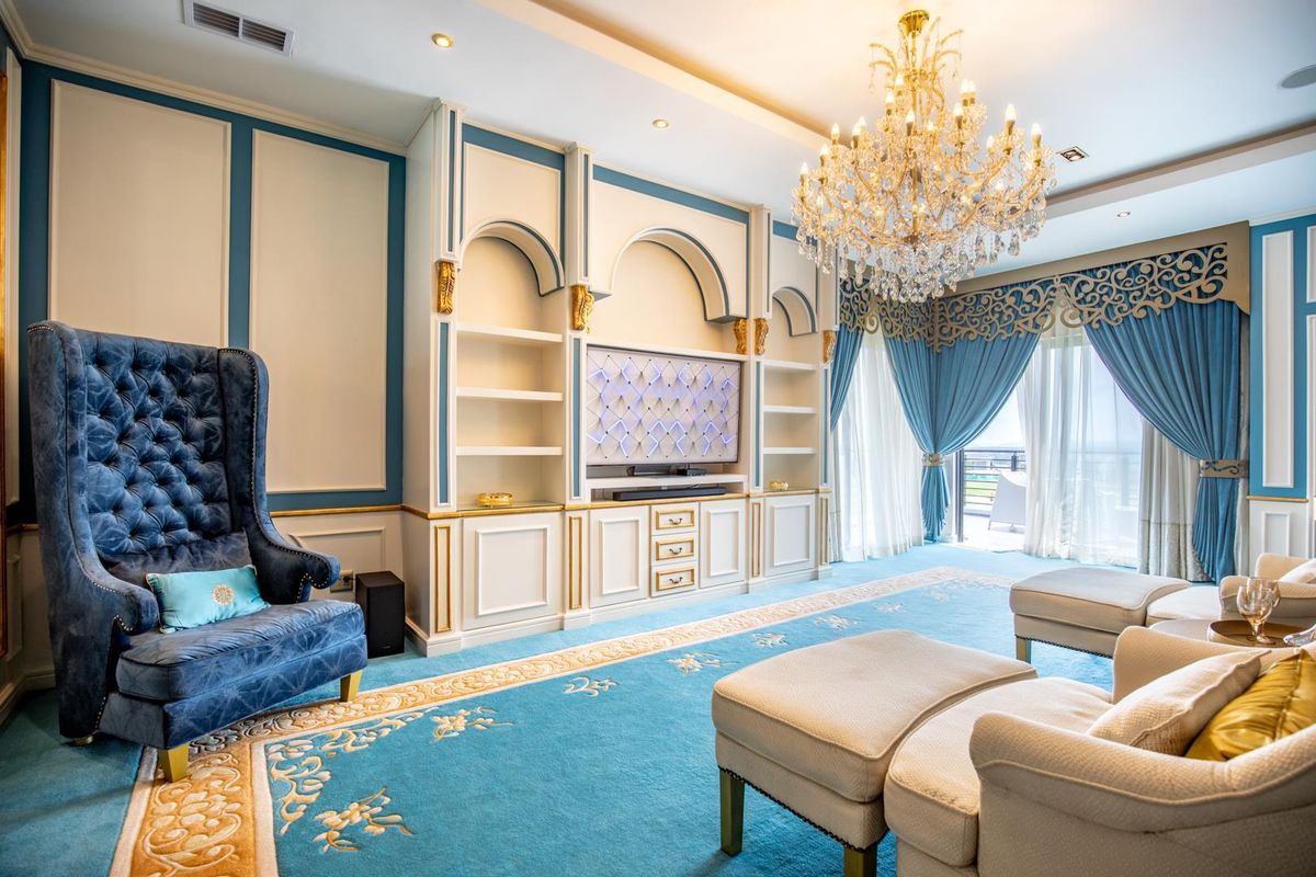 Elegant living room featuring custom built-in cabinetry, decorative wall paneling, recessed lighting, and a grand crystal chandelier.
