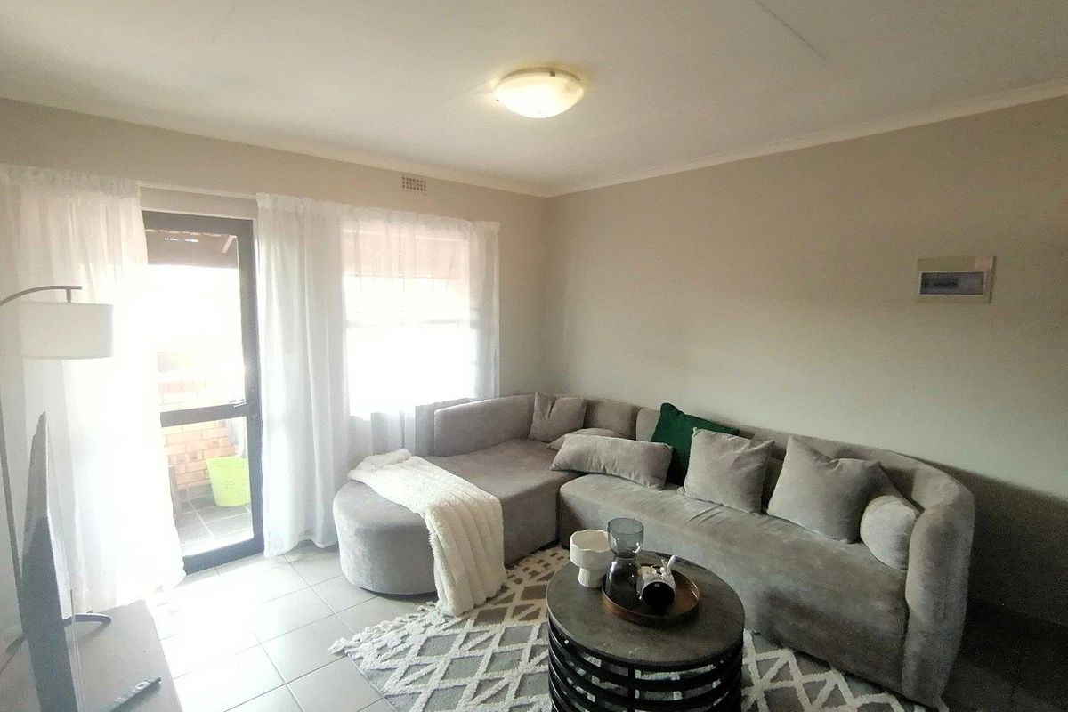 A comfortable living room featuring tiled flooring and a glass sliding door providing access to an outdoor area.