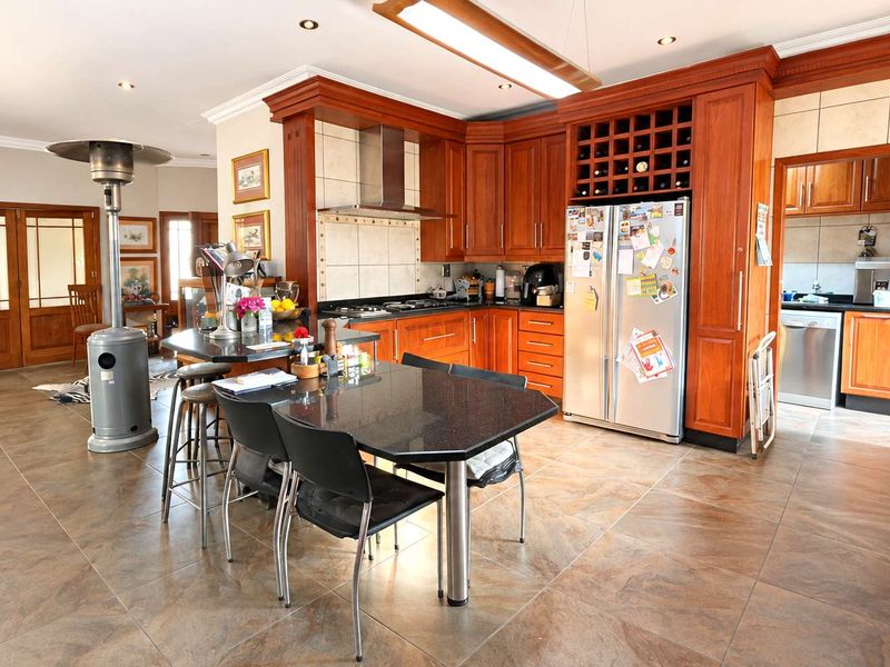 Spacious open-plan kitchen featuring warm wooden cabinetry, granite countertops, and a built-in wine rack, seamlessly flowing into the adjacent living area.