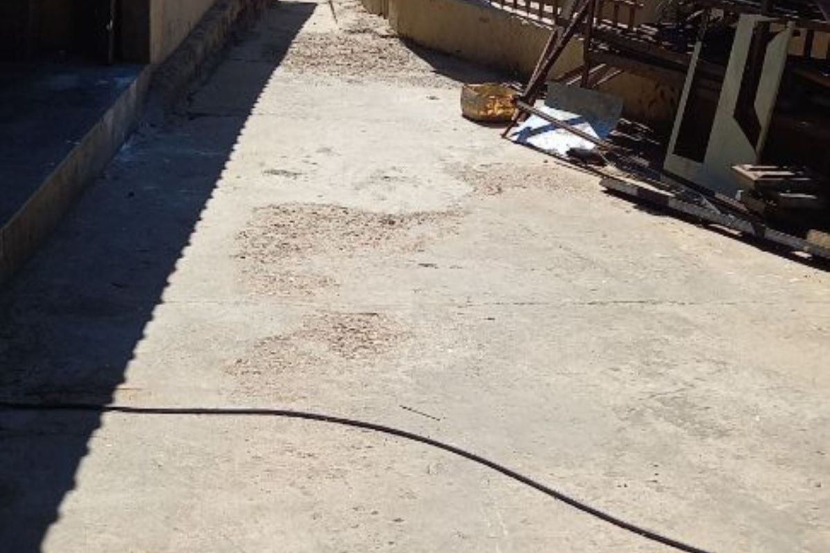 Exterior side passage featuring concrete paving and perimeter metal fencing with security spikes.