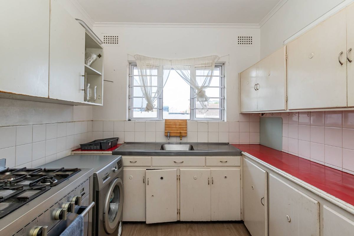 A dated kitchen featuring original cabinetry, a stainless steel sink, tiled backsplash, and a gas stove, offering significant potential for modernization and renovation.
