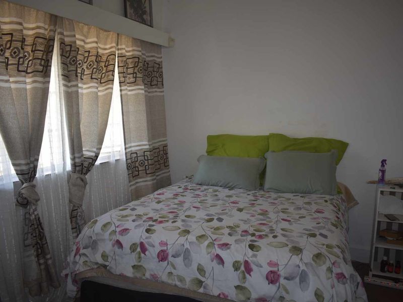 A standard bedroom featuring a window with installed curtain rails and neutral wall finishes.