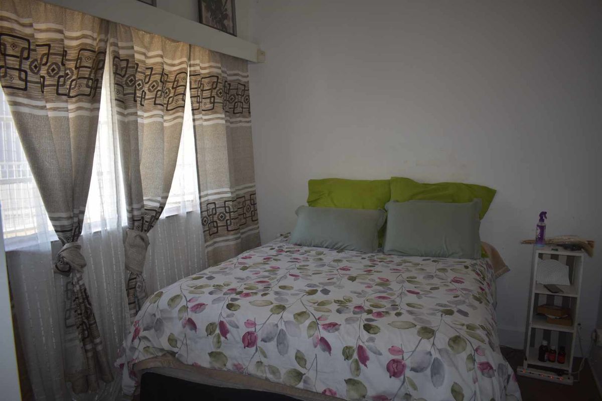 A standard bedroom featuring a window with installed curtain rails and neutral wall finishes.