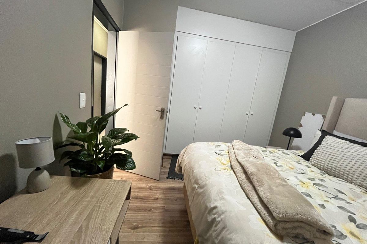 A well-maintained bedroom featuring laminate flooring and ample built-in cupboard storage, offering a clean and functional living space.