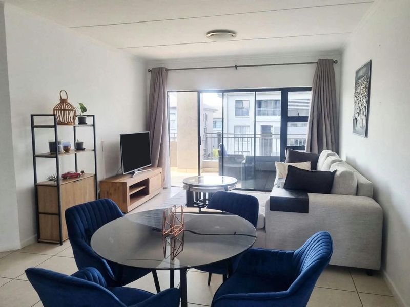 An open-plan living and dining area featuring neutral tiled flooring and large sliding glass doors that provide access to the balcony.