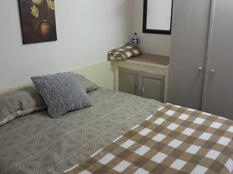 A functional bedroom featuring a built-in cupboard and neutral wall finishes, offering a practical space for rest.
