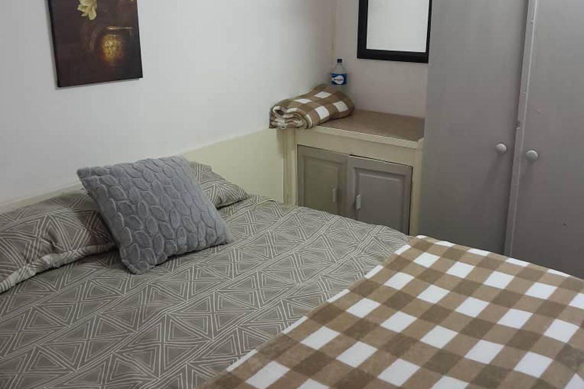 A functional bedroom featuring a built-in cupboard and neutral wall finishes, offering a practical space for rest.