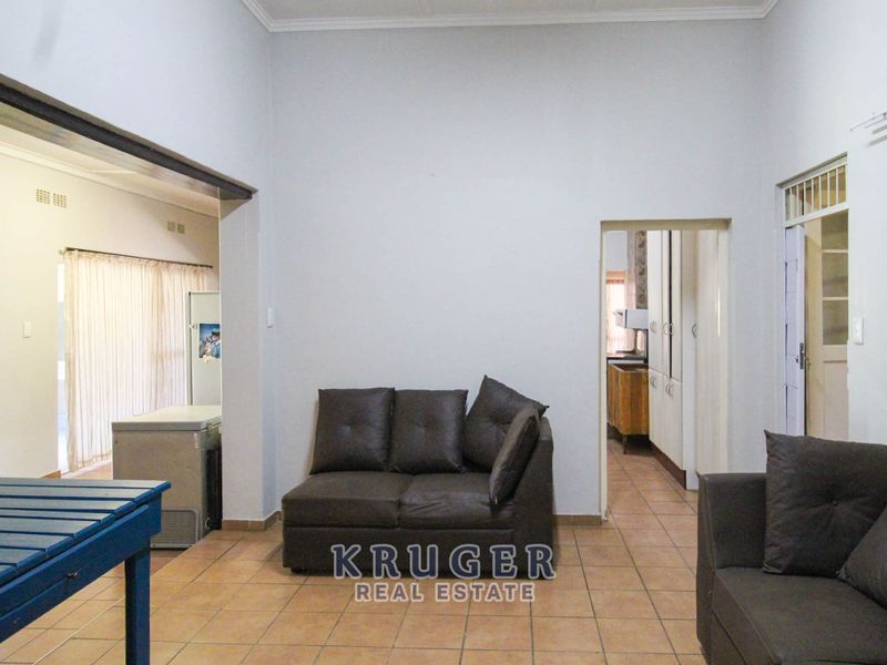 A spacious living area featuring tiled flooring and a coved ceiling, with an open-plan layout connecting to adjacent rooms.