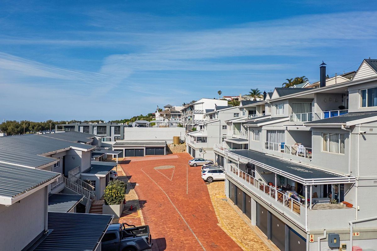 Aerial view of a multi-level apartment complex featuring metal roofing, paved driveway access, and private balconies.
