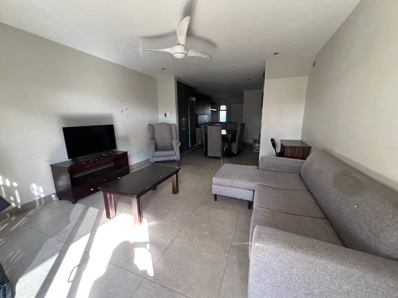 Open-plan living and dining area featuring tiled flooring, recessed lighting, and a ceiling fan, with an integrated kitchen visible in the background.