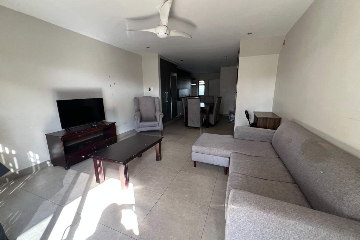 Open-plan living and dining area featuring tiled flooring, recessed lighting, and a ceiling fan, with an integrated kitchen visible in the background.