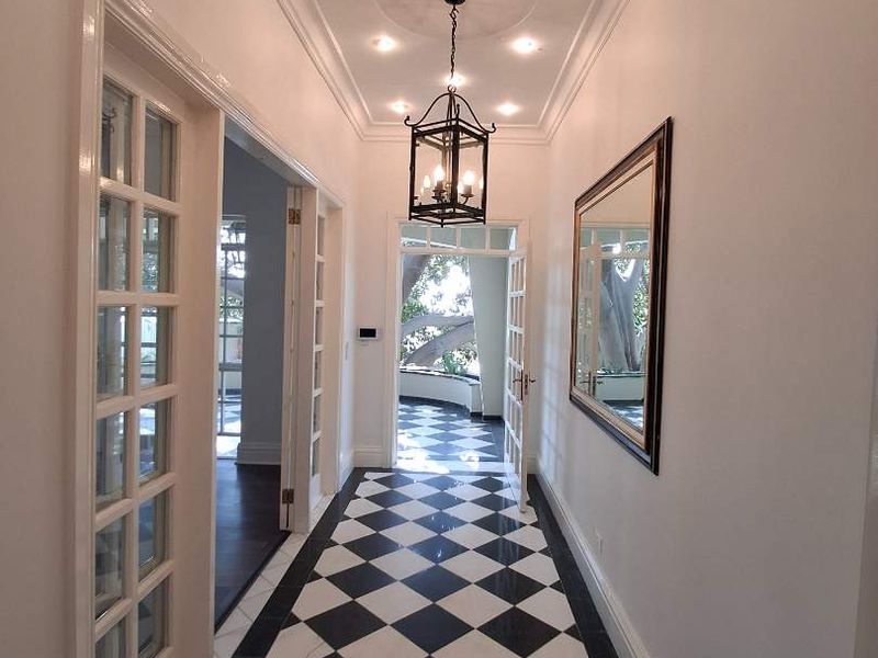 Elegant entrance hallway featuring classic black and white checkered marble flooring, recessed lighting, a decorative ceiling medallion, and glass-paneled french doors.