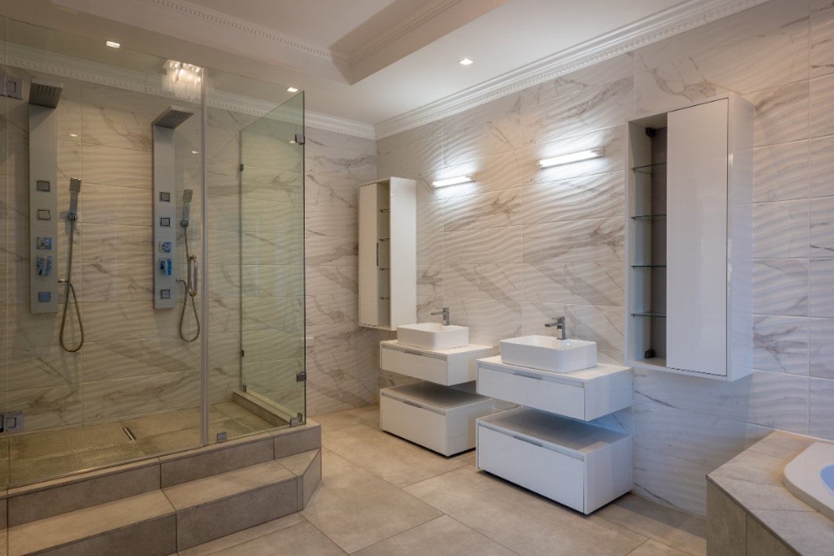 Modern bathroom featuring a spacious walk-in glass shower with dual shower heads, double floating vanity units, and elegant marble-effect wall tiling.