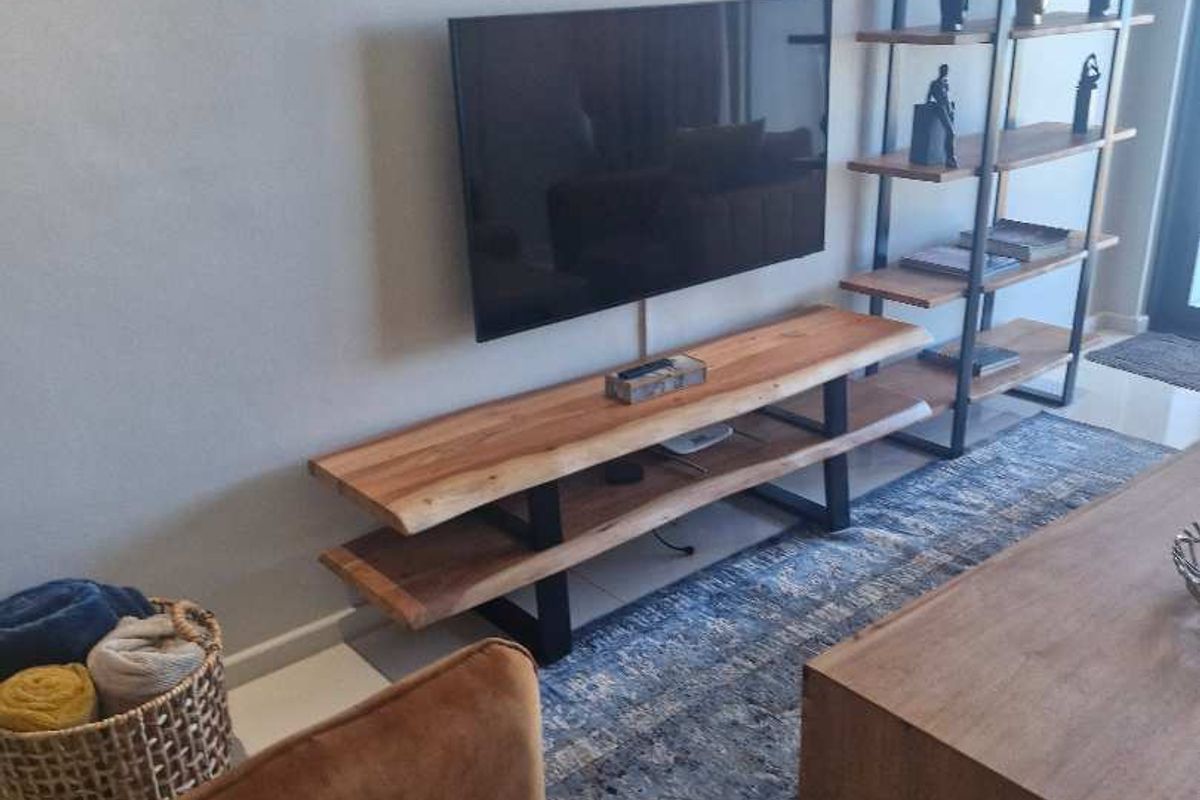 A modern living room featuring a wall-mounted television and sleek shelving unit, creating a functional and contemporary entertainment space.
