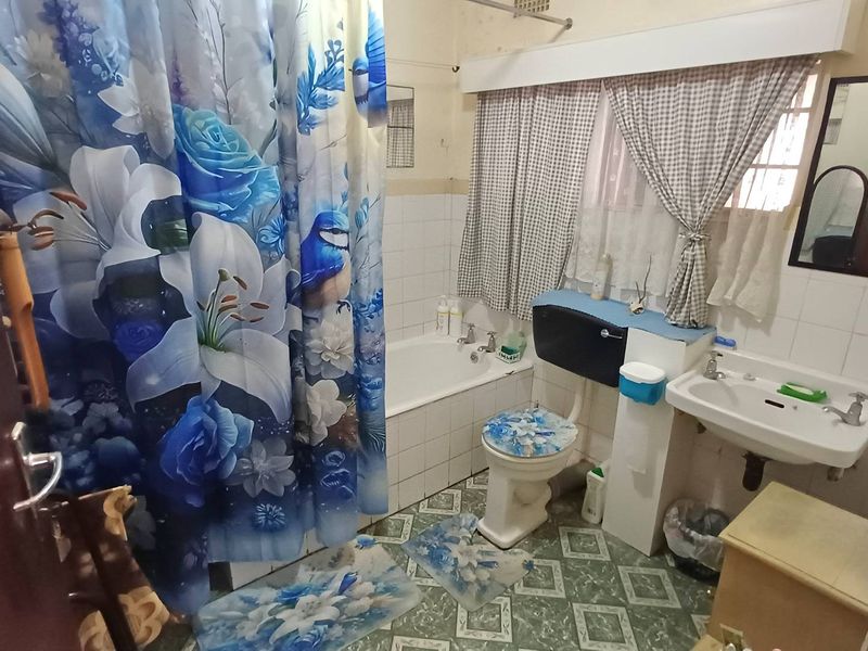 A dated bathroom featuring a standard bathtub, toilet, and washbasin with traditional tiled finishes, offering potential for a modern renovation.