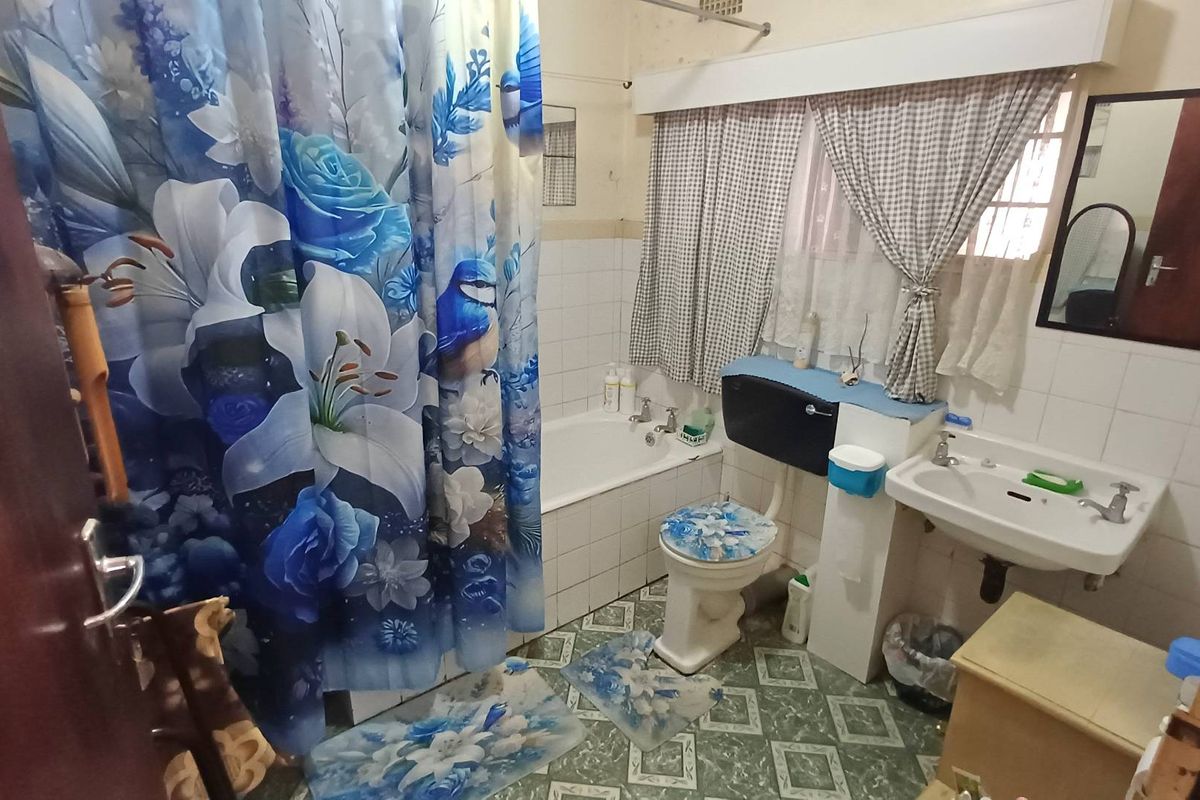 A dated bathroom featuring a standard bathtub, toilet, and washbasin with traditional tiled finishes, offering potential for a modern renovation.