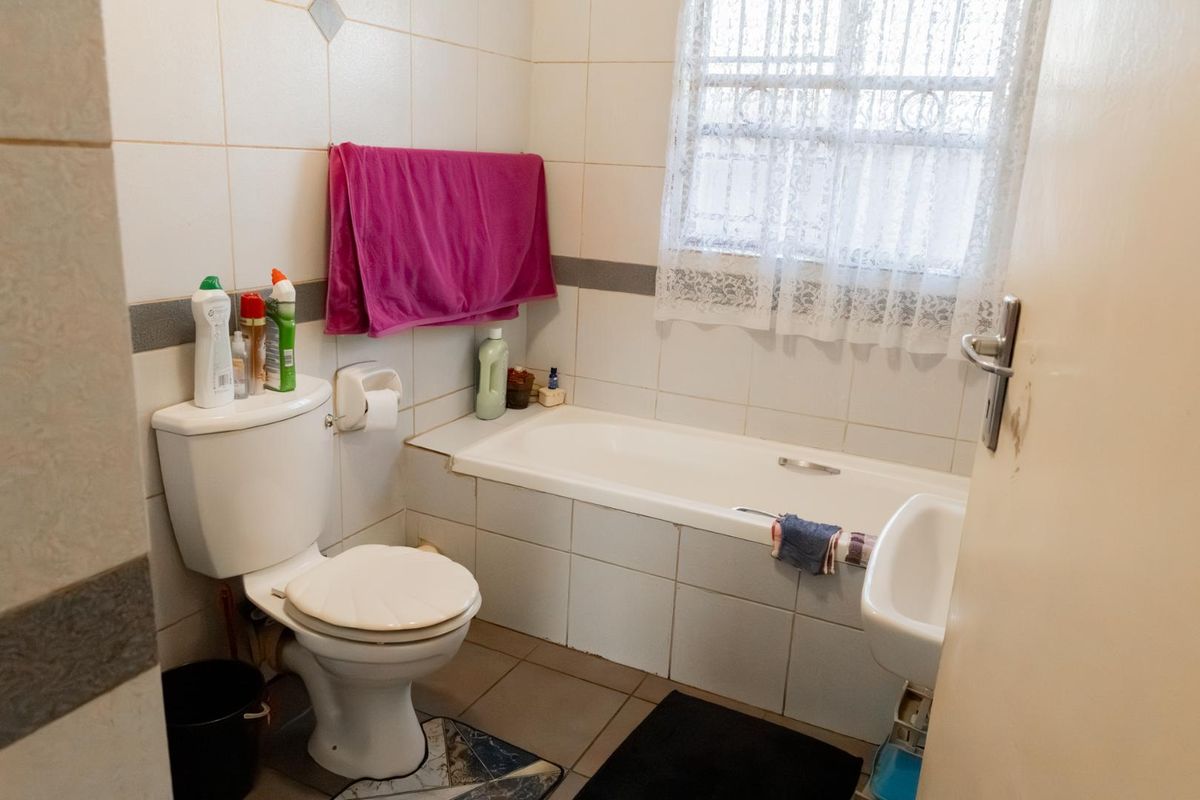 A functional bathroom featuring a standard bathtub, toilet, and basin with tiled walls and flooring.