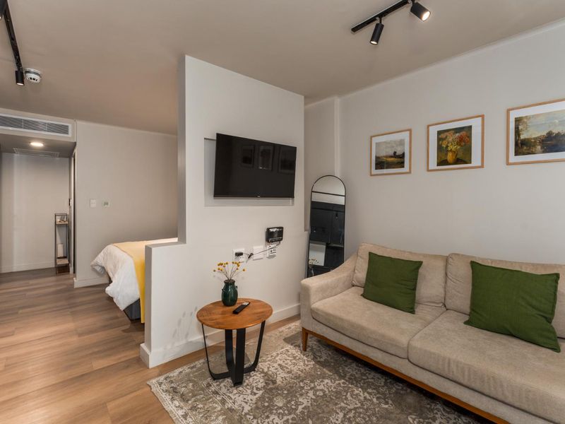 Modern open-plan studio apartment featuring a partition wall separating the living area from the bedroom, with track lighting and integrated air conditioning.